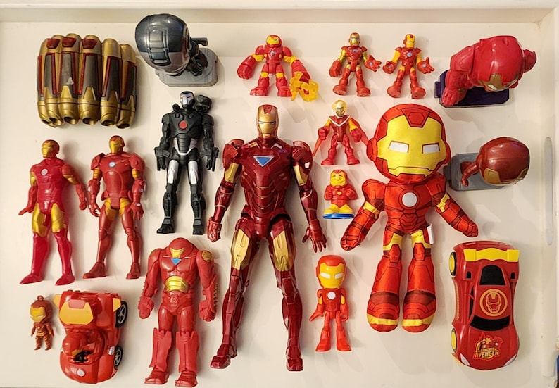 May include: A collection of Iron Man toys and figurines in various sizes and styles. The toys are primarily red and gold, with some black and silver accents. Includes action figures, a plush toy, and a toy car.