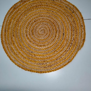 Può includere: Un sottopentola rotondo in iuta intrecciata con un motivo a spirale. Il sottopentola presenta fasce alternate di fibre di iuta beige naturale e giallo dorato. Adatto per l'arredamento della cucina e della sala da pranzo.