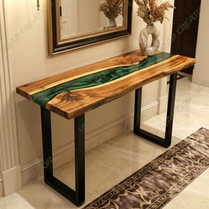 May include: A wooden console table with a live edge design and a vibrant green epoxy river. The table has a natural wood grain finish and is supported by black metal legs. The table is approximately 152 cm long.