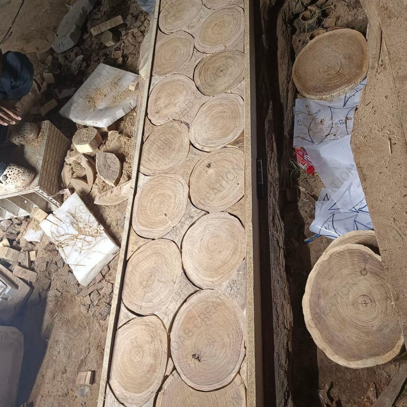 Puede incluir: Una tabla de madera con un mosaico de rodajas de madera circulares, mostrando patrones de vetas naturales. Las rodajas est&aacute;n dispuestas en un patr&oacute;n rectangular, creando una superficie texturizada. El color general es un marr&oacute;n c&aacute;lido y natural.