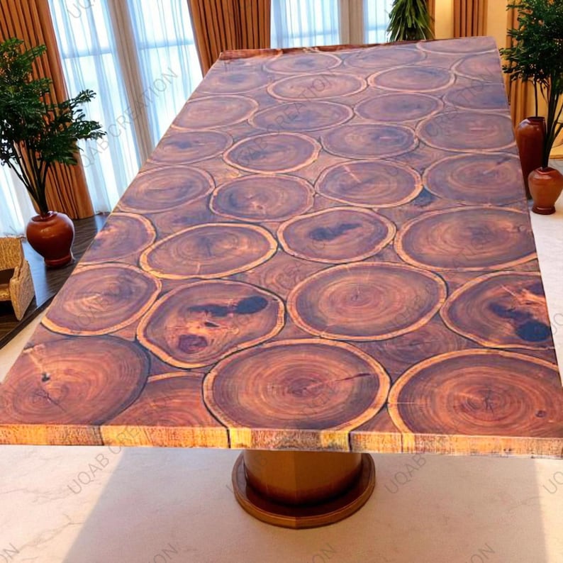 Puede incluir: Una mesa de madera rectangular grande con un dise&ntilde;o &uacute;nico. La tapa de la mesa est&aacute; hecha de numerosas rodajas de madera, creando un patr&oacute;n natural y org&aacute;nico. La mesa est&aacute; soportada por una base de pedestal redonda de madera. El color es marr&oacute;n c&aacute;lido.