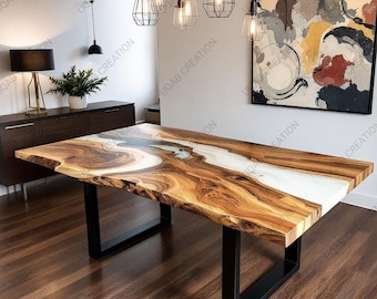 May include: A large, rectangular wooden dining table with a live edge and a white epoxy river. The table has a natural wood grain pattern and sits on black metal legs. The table is in a well-lit room with modern decor.