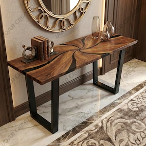 Puede incluir: Una consola de madera con un diseño único. La encimera presenta un patrón arremolinado de madera oscura y resina negra. Tiene patas de metal negro y está decorada con libros y jarrones. La mesa es una adición elegante a cualquier entrada o sala de estar.