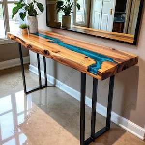 May include: A wooden console table with a live edge and a vibrant blue resin river. The table has a natural wood grain finish and sits on black metal legs. The table is approximately 60 inches long.