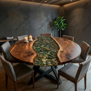 Pode incluir: Uma grande mesa de jantar redonda de madeira com um rio de pedras no centro. A mesa é rodeada por seis cadeiras cinzentas estofadas. Duas velas acesas estão sobre a mesa. A mesa tem um acabamento em madeira escura e uma base de metal preto. Diâmetro: aprox. 150 cm.