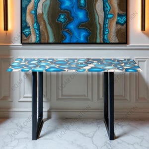 May include: A rectangular console table with a blue and white agate stone top and black metal legs. The tabletop features a pattern of blue and white circular shapes with gold accents. The table is approximately 48 inches long.