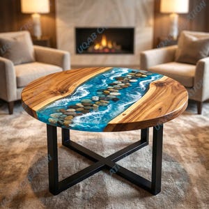Pode incluir: Mesa de centro redonda de madeira com design de rio. O centro apresenta resina epóxi azul com pedras embutidas, que simulam um rio. A mesa tem uma base de metal escuro e um acabamento de grão de madeira natural.