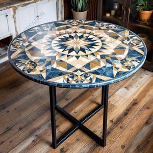 Op de afbeelding: Ronde tafel met een mozaïekblad met een geometrisch sterpatroon in blauw, bruin en wit. De tafel heeft een zwart metalen onderstel. De diameter van de tafel is ongeveer 100 cm.