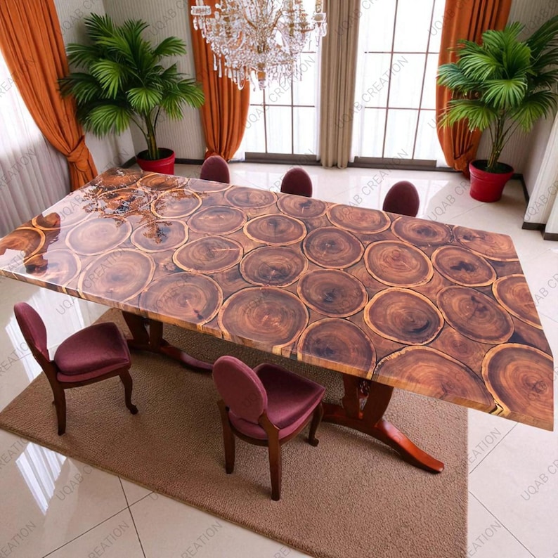 Puede incluir: Una gran mesa de comedor rectangular de madera con un dise&ntilde;o &uacute;nico. La superficie de la mesa est&aacute; hecha de rodajas de madera encapsuladas en resina transparente. La mesa est&aacute; sostenida por una base oscura y ornamentada. La habitaci&oacute;n cuenta con sillas burdeos, plantas y una l&aacute;mpara de ara&ntilde;a.