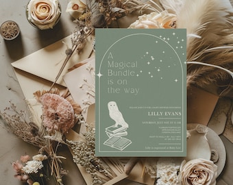 May include: A sage green baby shower invitation with the text "A Magical Bundle is on the way." The invitation features an owl illustration and floral accents. The invitation is surrounded by dried flowers, envelopes, and roses.