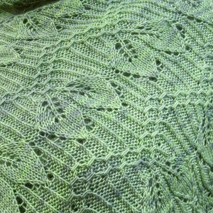 May include: A green and blue knitted shawl with a lacy pattern. The shawl is made of a soft yarn and has a delicate, flowing design.