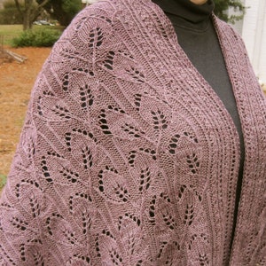 Könnte beinhalten: Ein mauvefarbenes gestricktes Tuch mit einem zarten Spitzenmuster. Das Tuch ist über die Schultern einer Person gelegt und aus einem weichen, leichten Garn gefertigt.