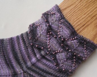 Könnte beinhalten: Lila und schwarze gestrickte Socken mit einem dekorativen Perlenmuster am oberen Rand.