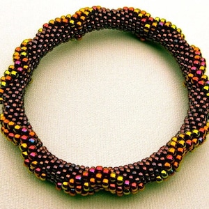 May include: A brown and gold beaded bracelet with a twisted design.