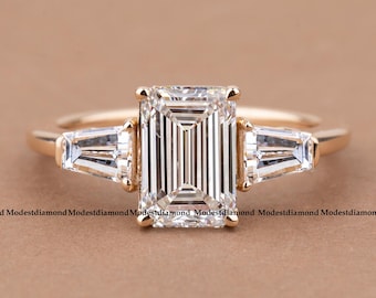 Anillo de compromiso de moissanita talla esmeralda en oro con piedras laterales baguette cónicas. Elegante anillo de tres piedras. Joyería nupcial única. Regalo para ella.
