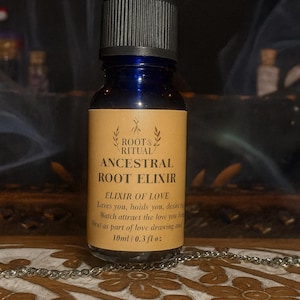 Puede incluir: Una botella de vidrio azul oscuro con un cuentagotas, etiquetada como "Ancestral Root Elixir" por Root & Ritual. La etiqueta beige tiene letras doradas e incluye el texto "Elixir of Love" y un volumen de 10 ml / 0,3 fl oz.