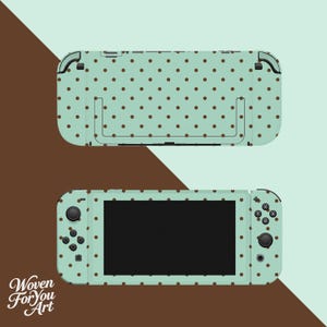 May include: A handheld gaming console featuring a light mint green skin with a repeating pattern of small dark brown polka dots. The device includes a front screen, directional buttons, a joystick, and action buttons, all covered in the same pattern.