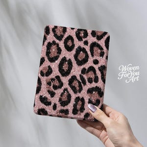 May include: A rectangular e-reader cover featuring a glittery rose gold and black leopard print pattern. The surface has a textured, sparkling appearance. The text Woven For You Art is printed in white on the right side of the cover.
