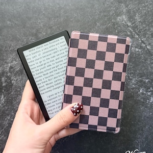 May include: An e-reader device with a black frame displaying text on its screen, paired with a protective cover featuring a mauve and black checkered pattern. The text on the screen begins with the words White church was Rosebank Union.