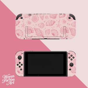 May include: A pink Nintendo Switch console with a matching shell pattern featuring various seashell illustrations. The design includes a top piece and the handheld console, both adorned with the same seashell pattern. The background is a gradient of pink.