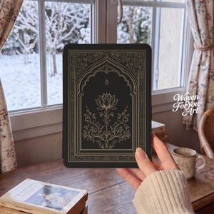 May include: A black e-reader case featuring a gold-colored line art illustration of a lotus flower centered within an arched frame. The design includes intricate floral and geometric border patterns. The text Woven For You Art is visible.