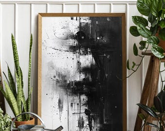 May include: Abstract black and white art print in a wooden frame. The artwork features a split composition with splatters, lines, and geometric shapes. The print is displayed on a wooden floor, with plants and a watering can in the foreground.