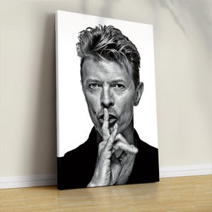 May include: Black and white portrait of a man with his finger to his lips, a gesture of silence. The image is a close-up, focusing on the man's face and hands. The artwork is mounted on a white canvas, leaning against a wall.