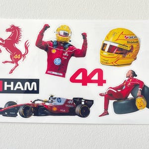 May include: A sheet of stickers featuring Formula 1 racing imagery. Includes a red race car, a yellow helmet, a red horse logo, the number 44, and the word "HAM". The stickers are on a white background.