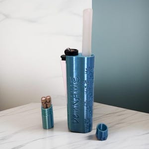 May include: A teal blue 3D-printed holder with a lighter and a white item inside. The holder has a cannabis leaf pattern and the word "DeinName" printed on it. A small teal blue container and a small container with two items are also present.