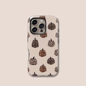 May include: A phone case with a repeating pattern of pumpkins in various shades of brown and tan, resembling a leopard print. The case has a beige background and a camera cutout.