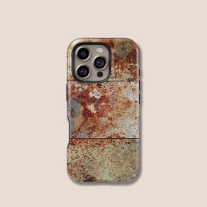 May include: A phone case with a weathered, rusty metal design. The case features a textured surface with shades of brown, orange, and gray, mimicking the look of aged metal. The case has a camera cutout for a multi-lens camera.