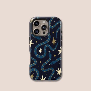 Può includere: Una custodia per telefono con sfondo blu scuro con un motivo ripetuto di serpenti blu, stelle dorate e punti dorati. La custodia ha una finitura lucida e un ritaglio per la fotocamera.
