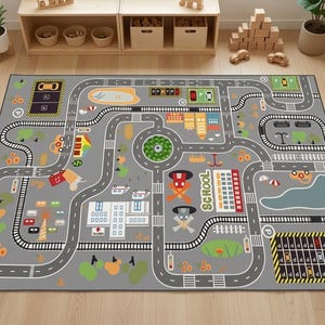 May include: A rectangular gray area rug featuring a colorful printed city map with roads, a railway track, a school building, a hospital, parking lots, green spaces, and various vehicles. The design includes a central roundabout and a pond.