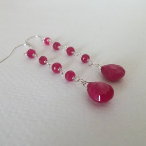 May include: A pair of long silver earrings with pink gemstone beads and teardrop-shaped pendants.