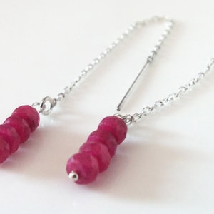 May include: A pair of silver chain earrings with a cluster of deep red gemstone beads hanging from each chain.