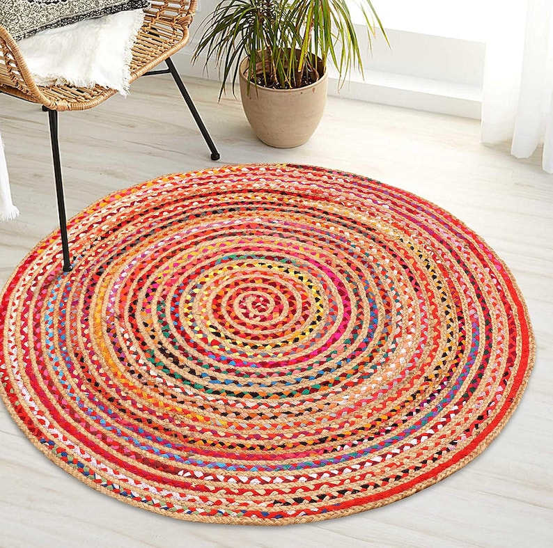 Puede incluir: Una alfombra redonda de yute con un dise&ntilde;o en espiral. La alfombra presenta una vibrante paleta de colores rojo, naranja, amarillo y azul. La alfombra tiene aproximadamente 152 cm de di&aacute;metro y es adecuada para uso en interiores.