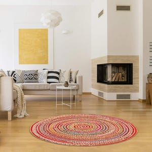 Puede incluir: Una alfombra redonda trenzada multicolor, con c&iacute;rculos conc&eacute;ntricos rojos, amarillos y azules. La alfombra est&aacute; colocada sobre un suelo de madera en un sal&oacute;n. El di&aacute;metro de la alfombra es de aproximadamente 152 cm.