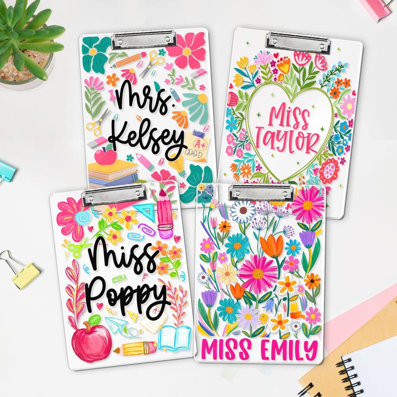 May include: Four white clipboards with floral designs and teacher names: Mrs. Kelsey, Miss Taylor, Miss Poppy, and Miss Emily. Each clipboard features colourful flowers, school supplies, and a silver clip.