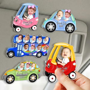 May include: A collection of car-shaped magnets featuring smiling babies. The magnets are in various colors, including pink, blue, green, and red. Each magnet has the text "Drive Safe Daddy".