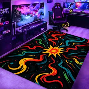 May include: A rectangular area rug with a black background and a colorful, abstract design. The rug features a central burst of yellow and orange, with radiating lines of red, blue, green, and yellow. The rug is placed in a gaming room.