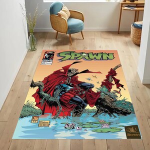 May include: A rectangular rug featuring a comic book cover design. The rug displays the title "SPAWN" in large, green letters. The artwork depicts a character in a red cape, set against a backdrop of water and an orange sky. The rug is placed on a wooden floor.