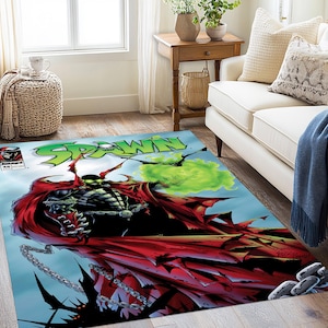 May include: Rectangular area rug featuring a comic book cover design. The rug displays the word "SPAWN" in green, with a red-caped character and a green energy blast. The rug has a blue background and a comic book cover design.