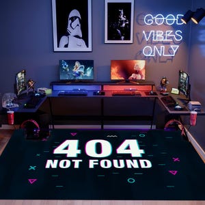 Peut inclure: Une configuration de salle de jeux avec deux bureaux d'ordinateur, chacun avec un moniteur, un clavier et une souris. La pièce présente des œuvres d'art encadrées de Star Wars et de Batman, et une enseigne au néon qui dit "GOOD VIBES ONLY". Un tapis au sol affiche le texte "404 NOT FOUND."