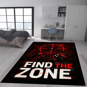 Könnte beinhalten: Schwarzer rechteckiger Teppich mit einem roten und weißen Gaming-Design. Das Design zeigt einen Controller, ein Fadenkreuz und den Text "FIND THE ZONE". Der Teppich liegt auf einem hellen Holzboden.