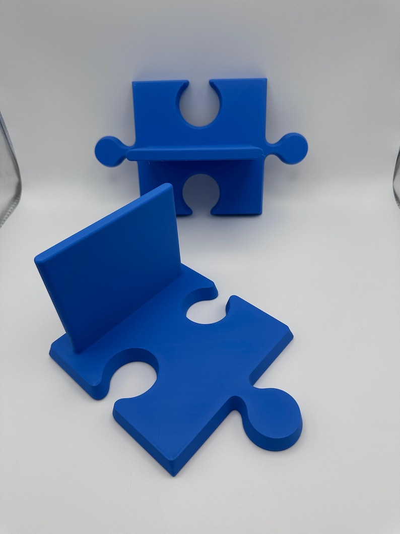 May include: Two blue puzzle piece-shaped shelves. One is upright, and the other is lying flat. The shelves are a solid, vibrant blue color and have a smooth, matte finish. The design is simple and modern, suitable for home decor.