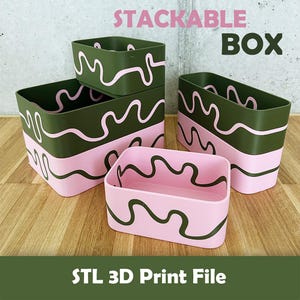 May include: A set of rectangular stackable boxes featuring a wavy line pattern. The boxes are colored in olive green and light pink, with the text STACKABLE BOX and STL 3D Print File visible. The containers have rounded corners and open tops.