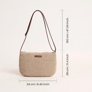 Pu&ograve; includere: Borsa a tracolla beige intrecciata con cinturino in pelle marrone. La borsa &egrave; larga 24 cm, alta 29 cm e il cinturino &egrave; lungo 120 cm. Ha una forma rettangolare con angoli arrotondati e una piccola etichetta in pelle marrone.