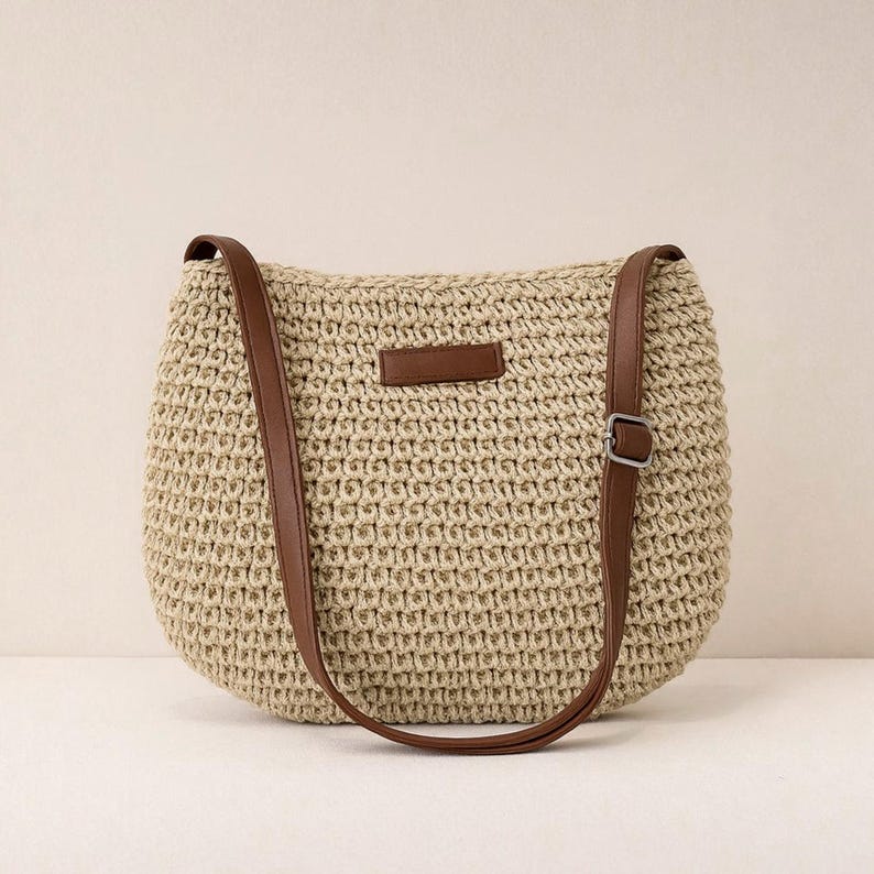 Pu&ograve; includere: Borsa a tracolla beige intrecciata con cinturini in similpelle marrone e una piccola toppa rettangolare. La borsa ha una forma arrotondata e una fibbia sul cinturino per la regolazione. La borsa &egrave; realizzata in materiale intrecciato.