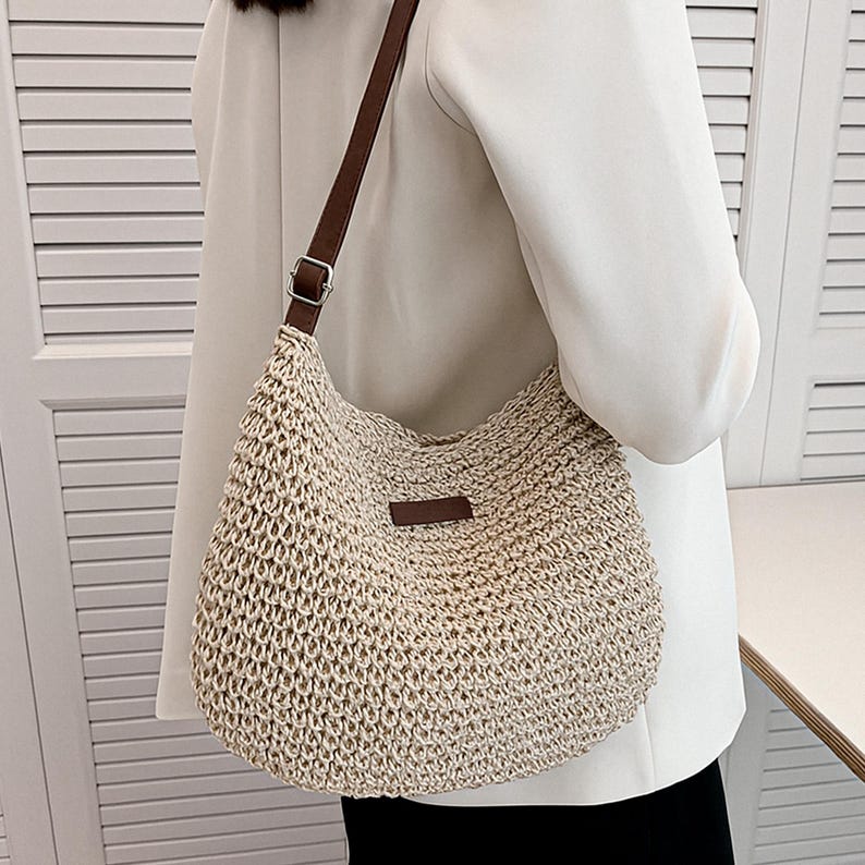 Pu&ograve; includere: Borsa a tracolla beige intrecciata con cinturino in pelle marrone e una piccola toppa rettangolare in pelle marrone. La borsa &egrave; realizzata in un materiale strutturato a trama aperta e ha uno stile casual e rilassato.