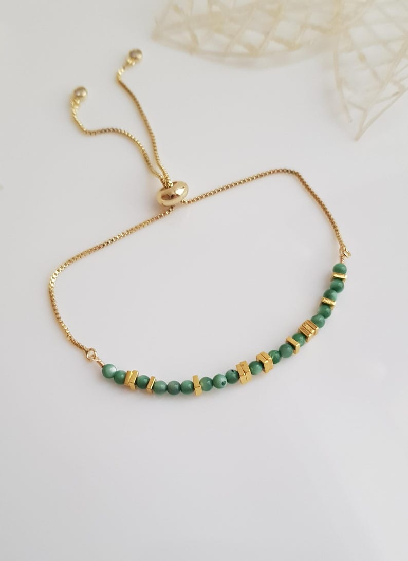 Puede incluir: Pulsera dorada ajustable con una fina cadena. Presenta peque&ntilde;as cuentas verdes redondas y detalles rectangulares dorados. La pulsera tiene un cierre deslizante para un ajuste f&aacute;cil.